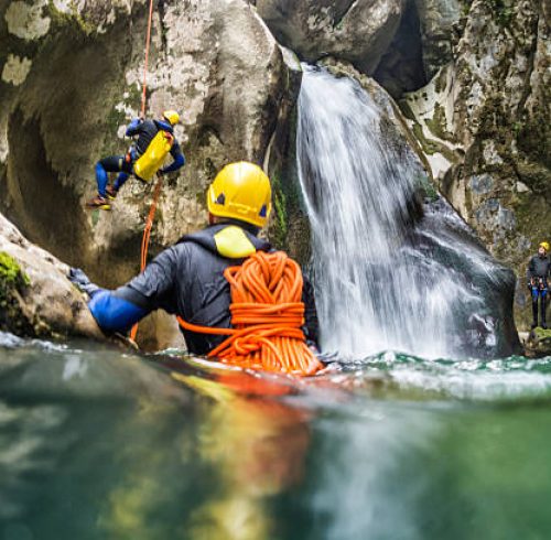 Shot from the water of extreme canyoning team members in the mountain cave.